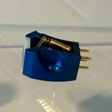 Close-up of a blue four-pin electrical connector with gold-plated pins on a light surface.