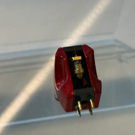 Close-up of a red plastic electrical connector with brass terminals on a metal surface, wiring visible inside the housing.