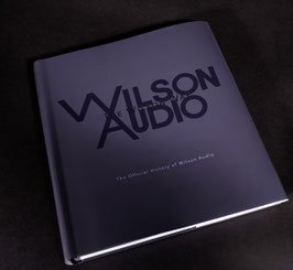 Purple hardcover booklet titled 'Wilson Audio' lying on a dark fabric surface.