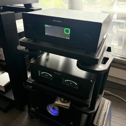 Black Audio Research stereo amplifier on a metal rack, with a green LED display and blue-lit meters beside vinyl records and other gear.