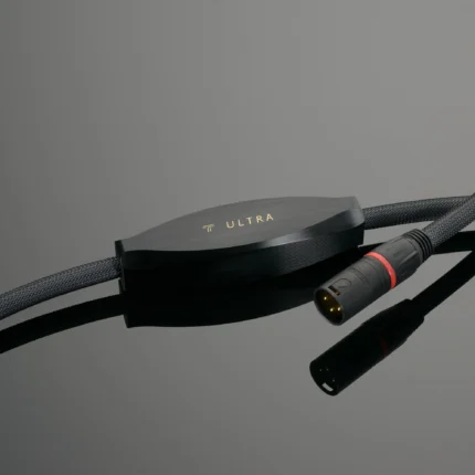 Close-up of a black electronic device with gold 'ULTRA' branding and braided cables crossing the frame on a gray background.